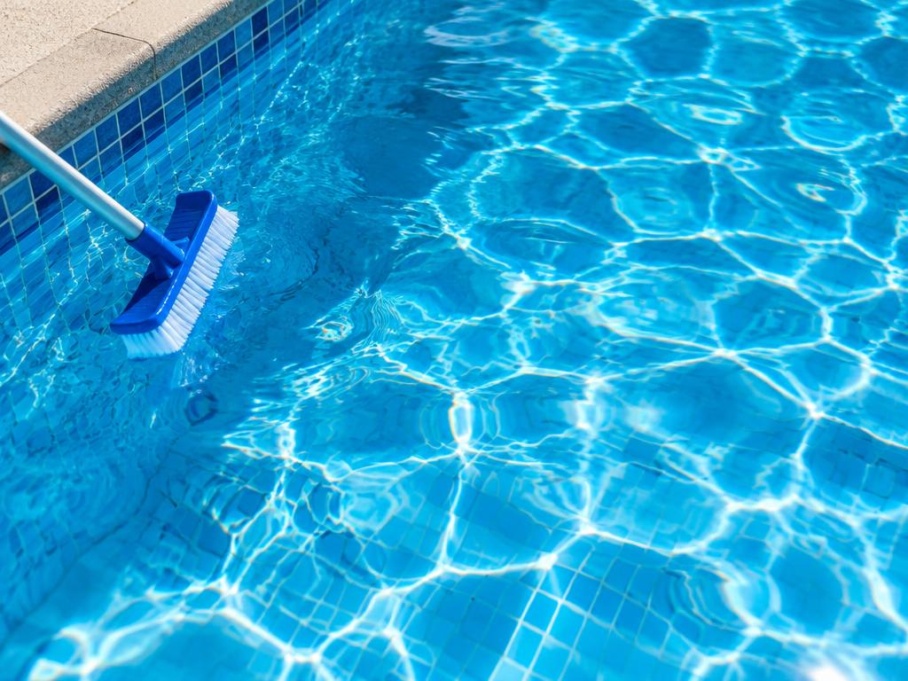 Brushing pool tile during a weekly pool cleaning